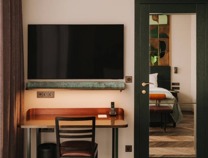 Nowoczesny hotelowy pokój z biurkiem, krzesłem, dużym telewizorem i lustrem na ścianie, eleganckie drewniane podłogi