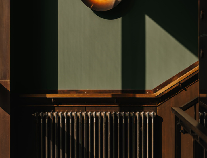 Wewnętrzne oświetlenie i klasyczny metalowy grzejnik na ścianie z zielonym tłem i drewnianymi detalami