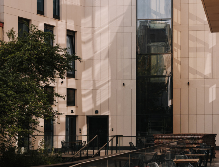 Nowoczesny hotel z zewnętrznym tarasem z stolikami i krzesłami do wypoczynku na świeżym powietrzu