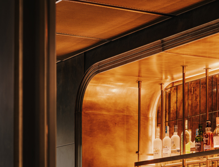 Elegancki bar hotelowy z oświetleniem w ciepłych odcieniach i półkami z różnorodnymi alkoholami