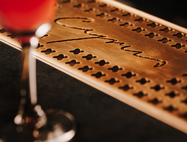 Kolorowy koktajl z plasterkiem cytryny na szklance stoi na barze z miedzianą podkładką z ozdobnym wzorem