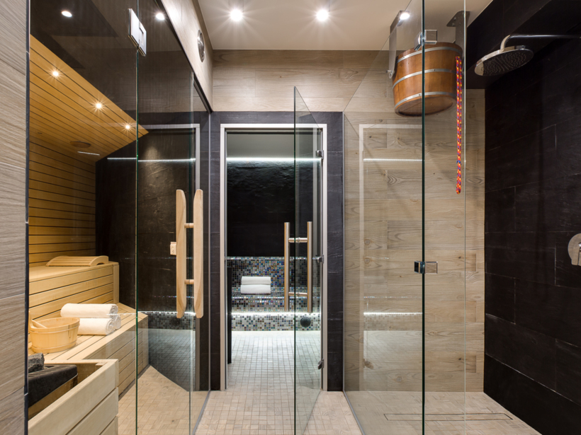 Nowoczesna sauna i pokój parowy z mozaikowymi ławkami i drewnianym wiadrem natryskowym w ekskluzywnym spa hotelowym