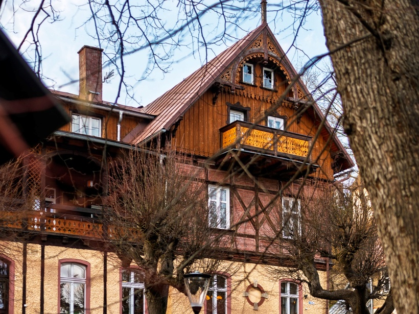 Historyczny, przytulny pensjonat w stylu szwajcarskiego domu z drewnianym szczytem i zdobionym balkonem, kamienna podmurówka