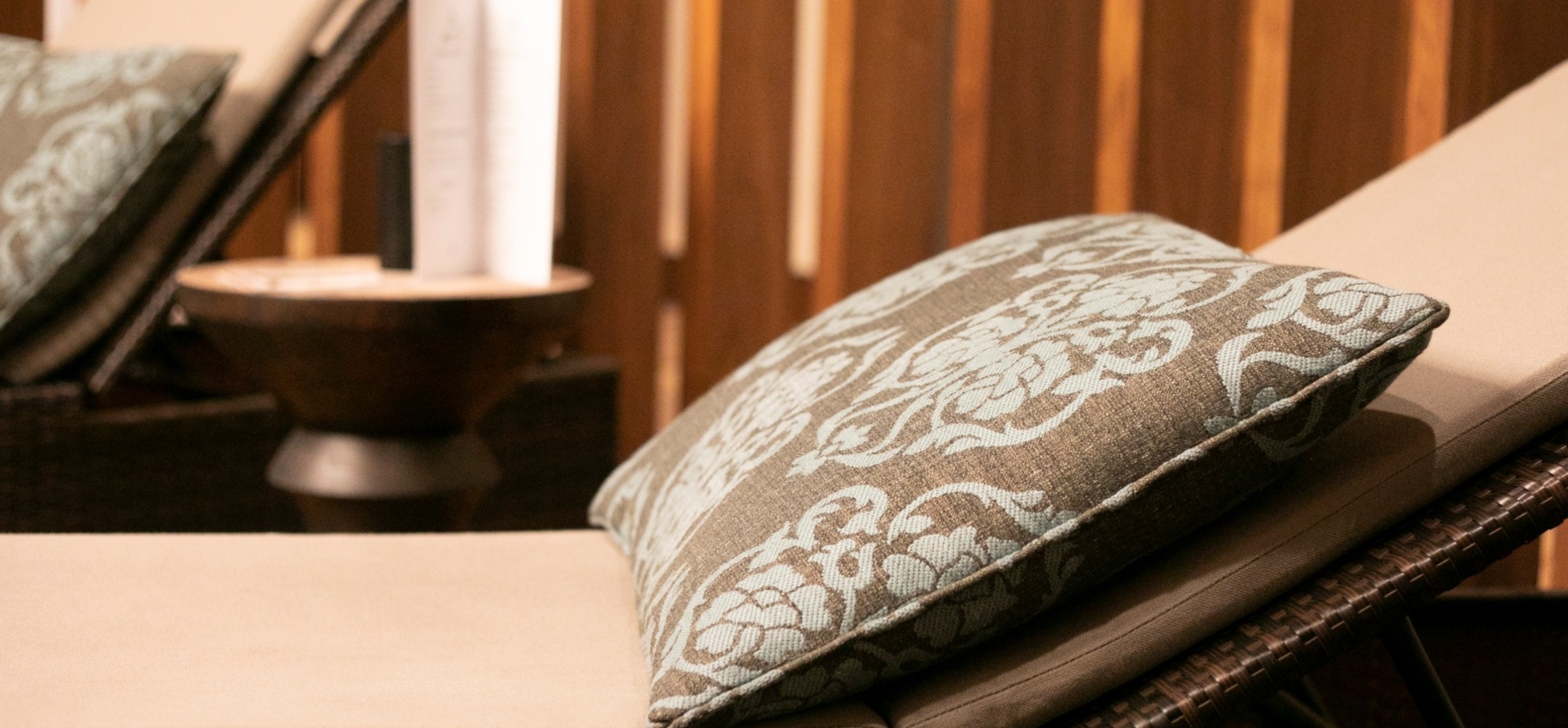 Leżaki z miękkimi poduszkami i eleganckim wzorem, otoczone drewnianymi panelami dla relaksu w spa.