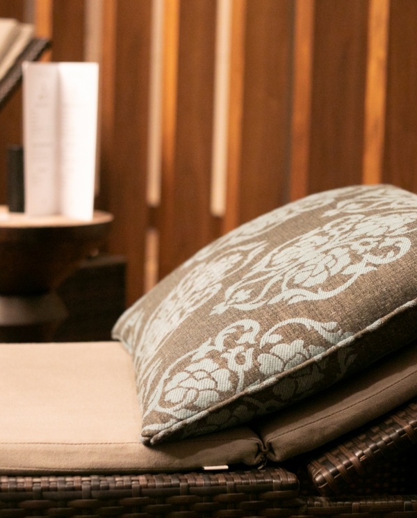 Leżaki z miękkimi poduszkami i eleganckim wzorem, otoczone drewnianymi panelami dla relaksu w spa.