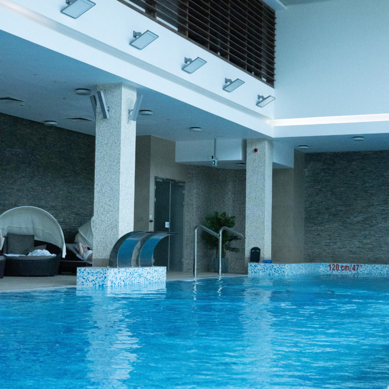 Przytulny hotelowy basen wewnętrzny z masażerami wodnymi i komfortowymi leżakami z baldachimem, nowoczesne oświetlenie