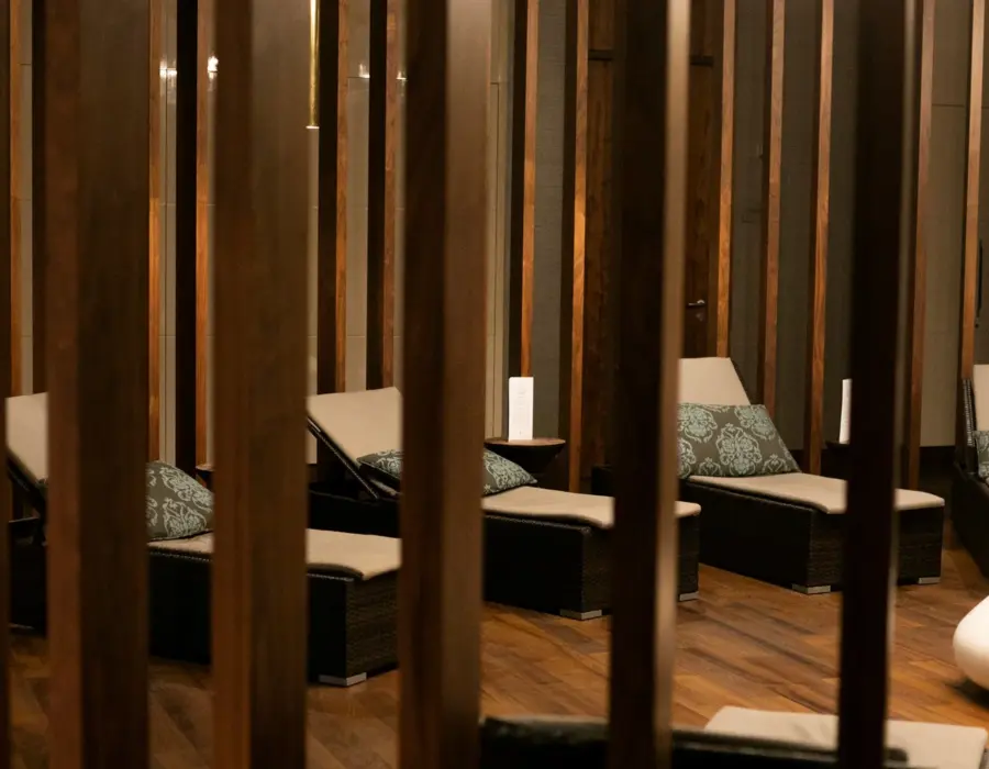 Strefa relaksu ze skórzanymi leżakami, poduszkami i drewnianymi dekoracjami w przytulnym wnętrzu spa.