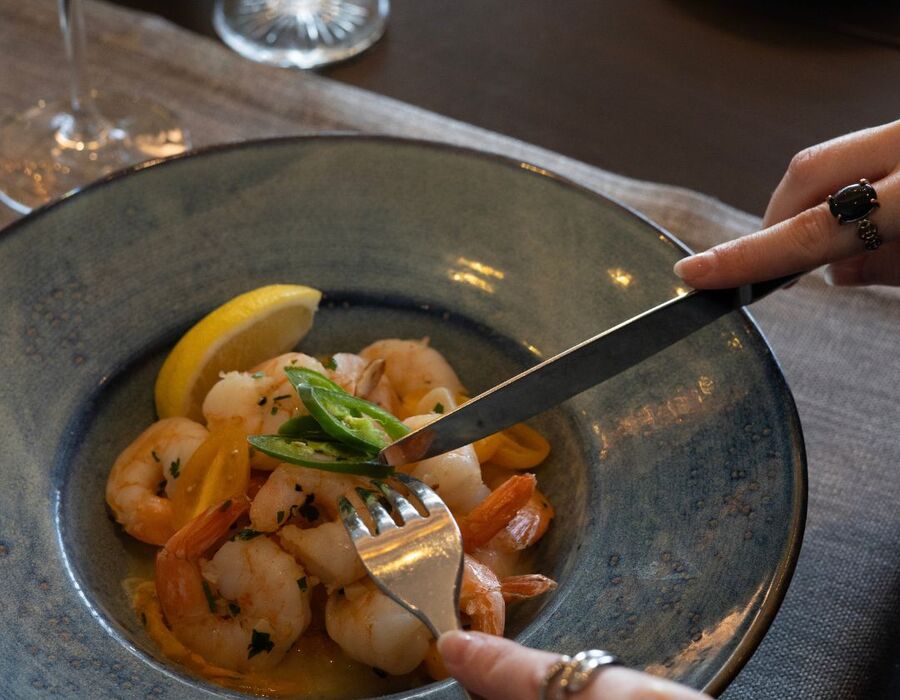 Delikatne krewetki podane z cytryną i plasterkami chili w eleganckim talerzu, idealne danie w hotelowej restauracji