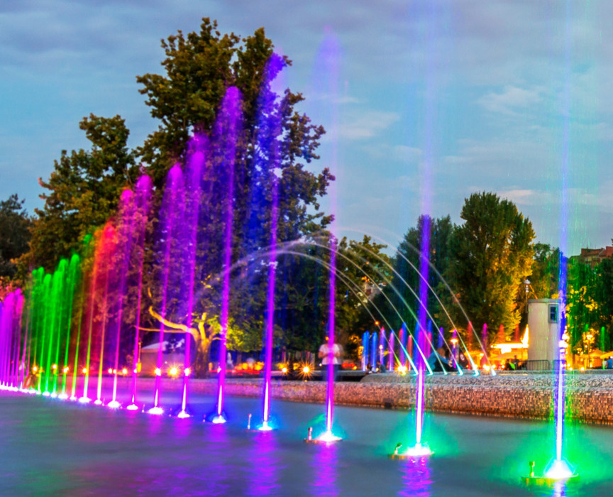 Kolorowa fontanna świetlna wieczorem w parku hotelowym z drzewami i oświetlonym otoczeniem