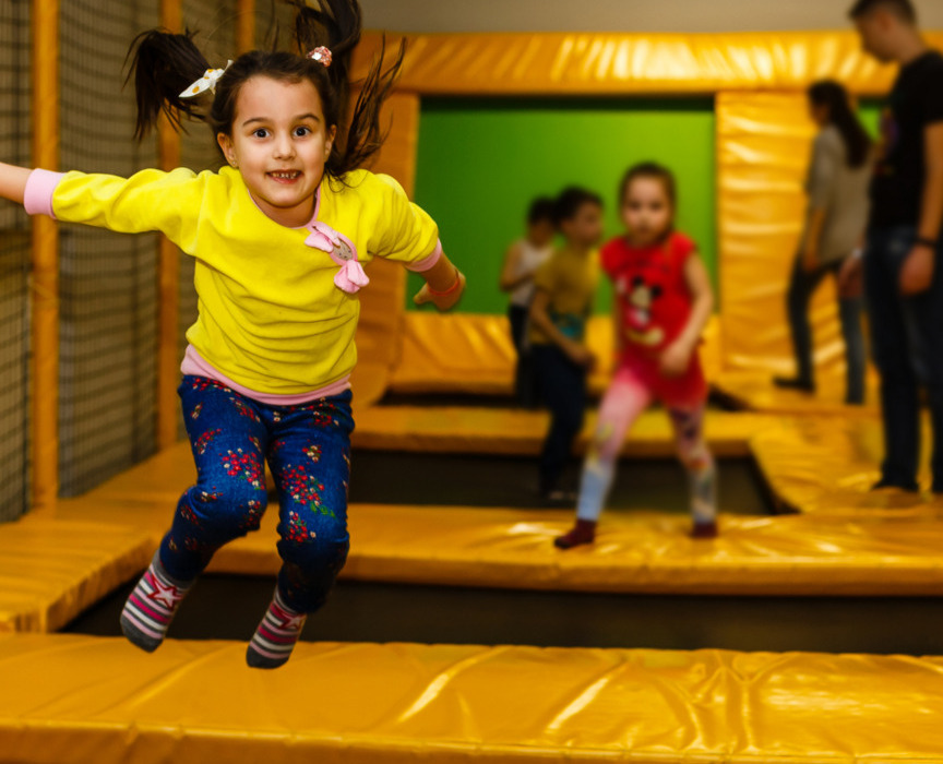 Dzieci bawiące się na żółtych trampolinach w kolorowej sali zabaw w hotelu, radosna i dynamiczna atmosfera