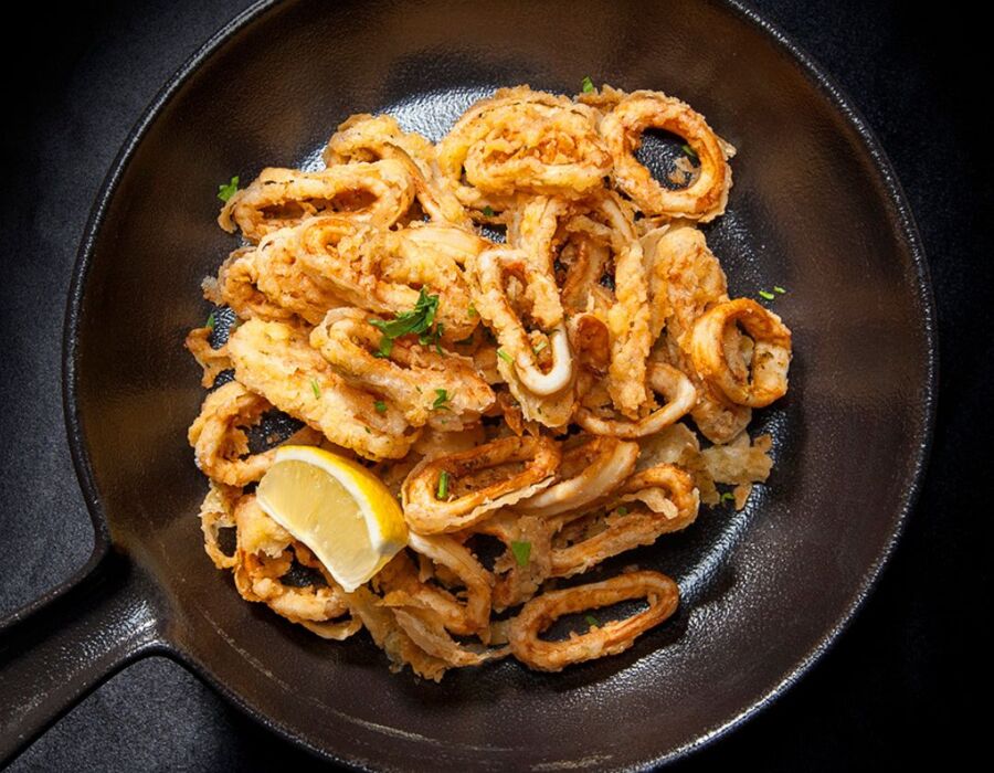 Chrupiące kalmary z patelni podane z ćwiartką cytryny i posiekaną pietruszką, idealne na lekki przystawkę