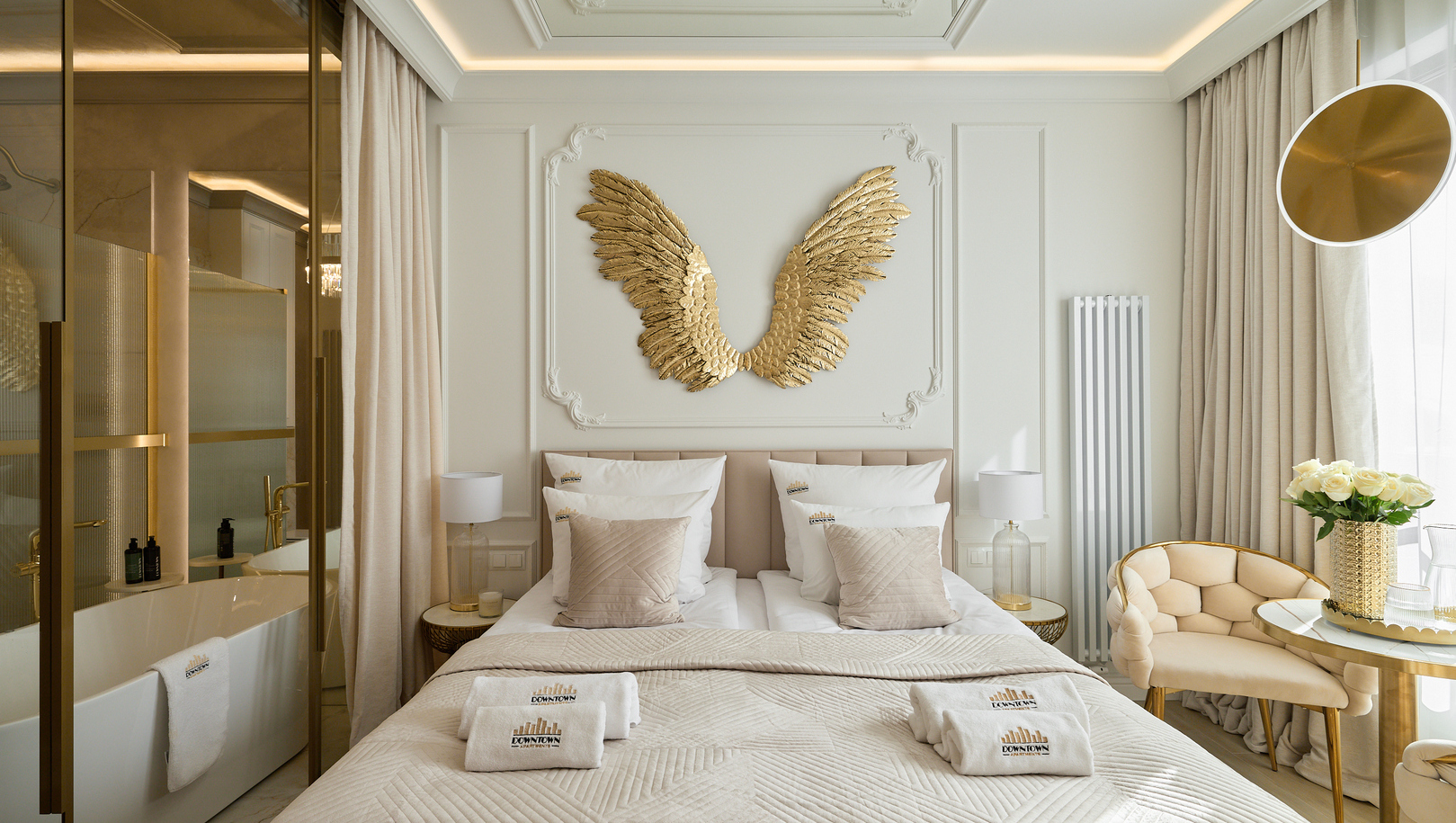 Elegancki pokój z dwiema łóżkami, beżową pikowaną pościelą, złotymi skrzydłami na ścianie i przeszkloną łazienką z wolnostojącą wanną.