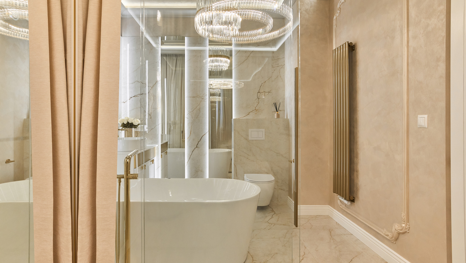 Luksusowa łazienka z marmurem, wolnostojącą wanną, kryształowym żyrandolem, złotymi armaturami i szklaną przegrodą.