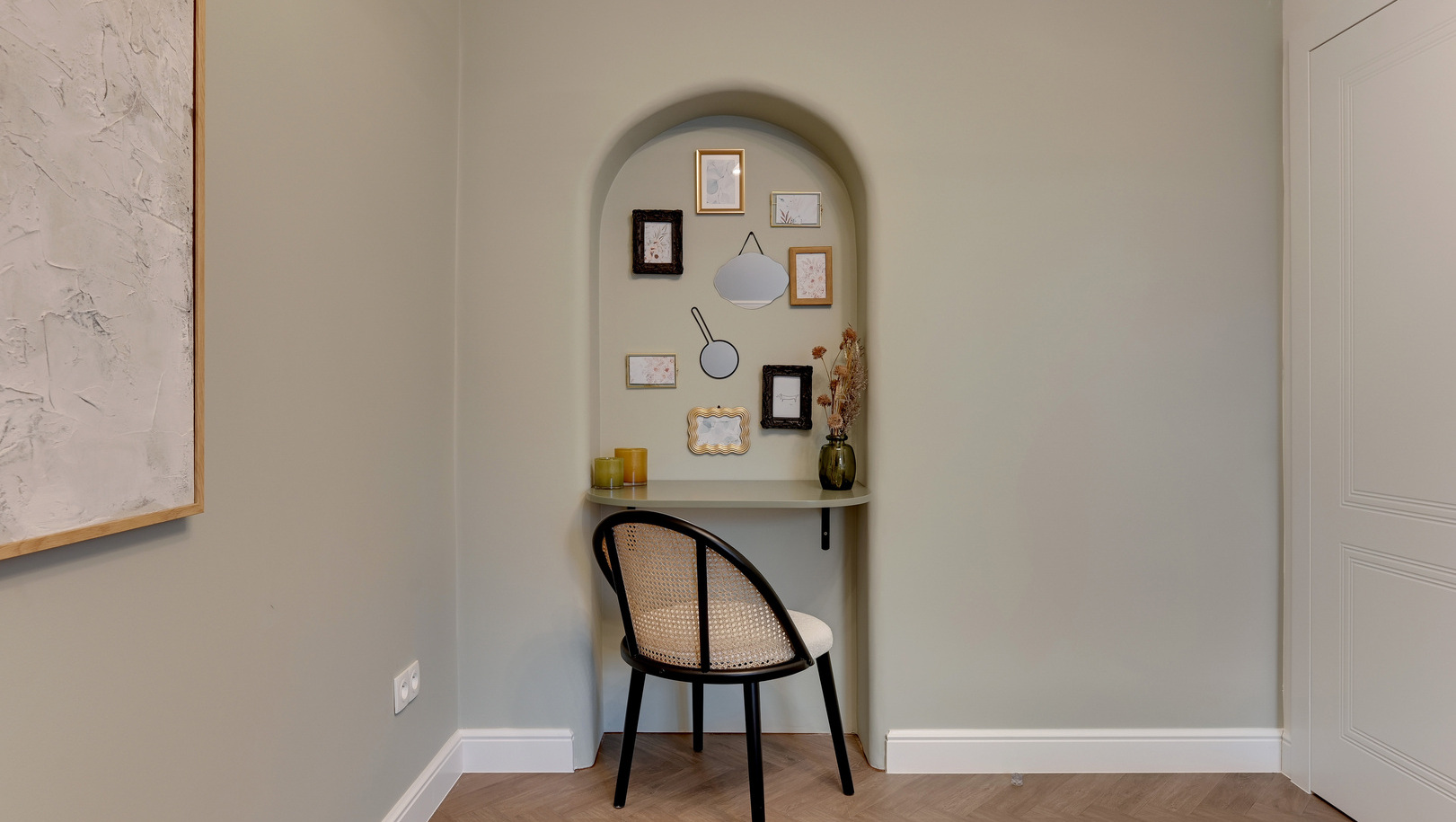 Łukowa wnęka z biurkiem, krzesłem z plecionką, obrazami, suchymi kwiatami i świecami — przytulne miejsce do pracy