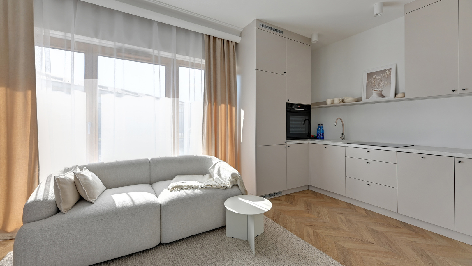 Jasne studio z aneksem kuchennym, piekarnikiem i zlewem, wygodną sofą, zwiewnymi zasłonami i podłogą w jodełkę