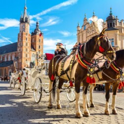Udekorowane bryczki na słonecznym, brukowanym rynku przy gotyckim kościele i ozdobnych sukiennicach — przejażdżki po mieście
