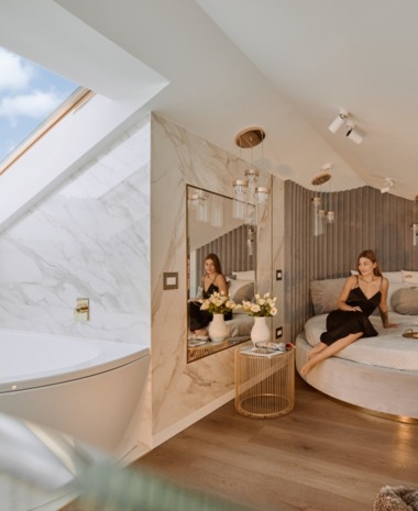 Antresolowy apartament z okrągłym łóżkiem, wolnostojącą wanną pod świetlikiem, marmurowymi detalami i odpoczywającą gościnią