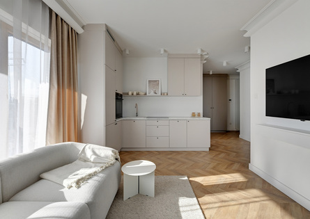 Jasny apartament typu studio w neutralnych barwach, otwarta kuchnia z marmurowym blatem, wygodna sofa i telewizor