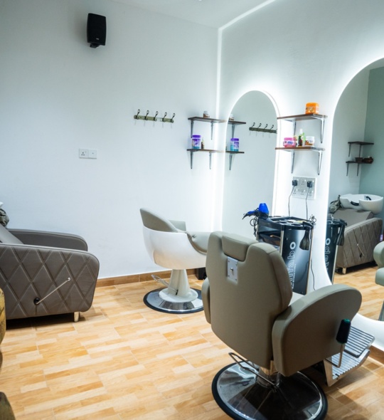 Modern hair salon with comfortable styling chairs, backwash basins, illuminated mirrors, and shelves stocked with hair care products