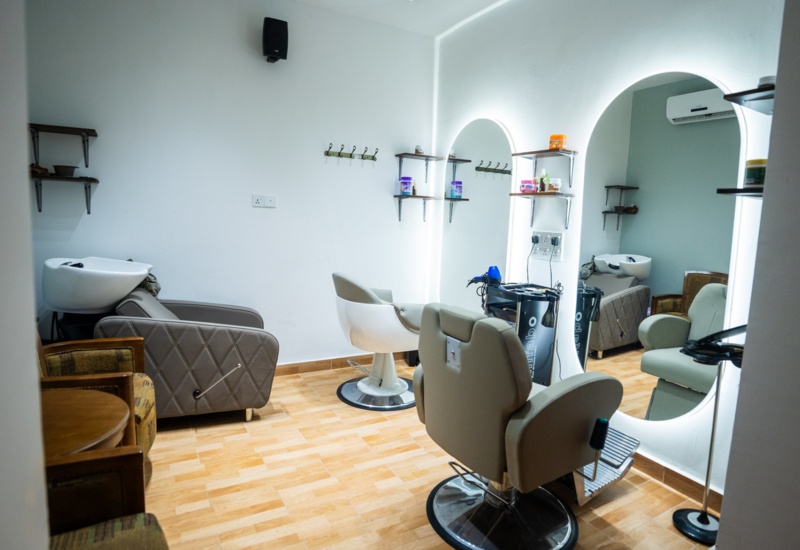 Modern hair salon with comfortable styling chairs, backwash basins, illuminated mirrors, and shelves stocked with hair care products