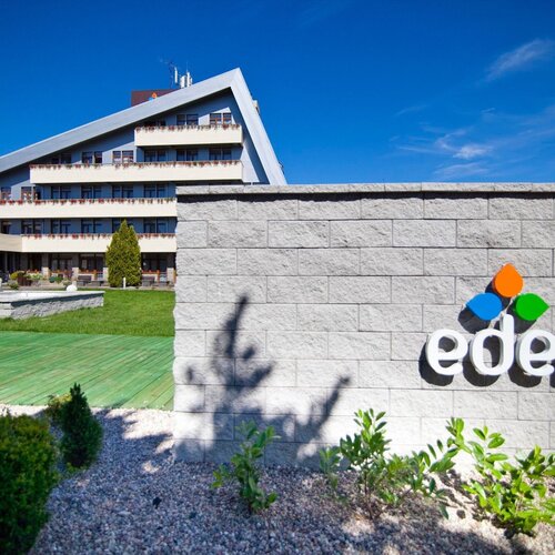 Hotel Eden with a slanted roof, tiered balconies covered in flowers, a green patio, a terrace and a visible logo.