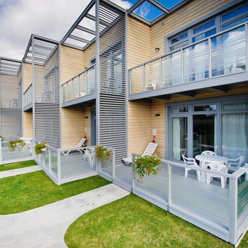 Modern apartments with wooden facade, private terraces with glass balustrades, sunbeds and a table