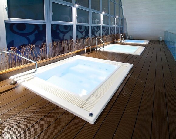 Three built-in jacuzzis on a wooden spa terrace with steel handrails, decorative panels and mood lighting.