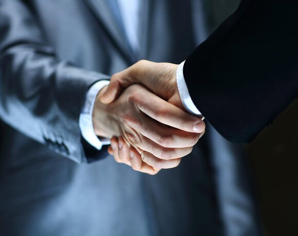 A handshake between two people in suits — a greeting after a business meeting in the hotel's conference room