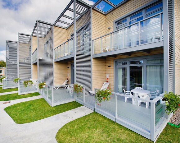 Nowoczesne apartamenty z drewnianą elewacją, prywatnymi tarasami ze szklanymi balustradami, leżakami i stolikiem