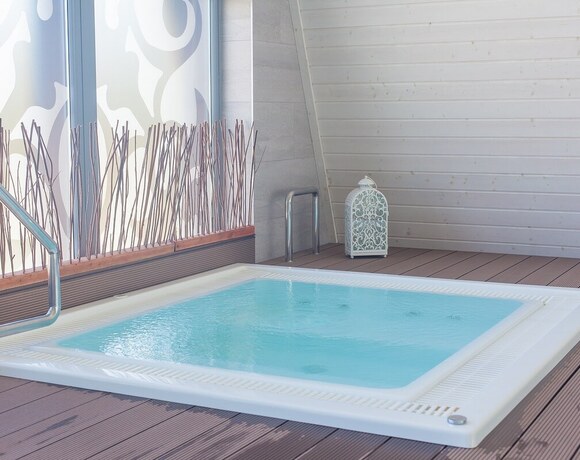 Private jacuzzi in the hotel spa: a heated massage tub, wooden terrace, decorative glazing and a decorative lantern