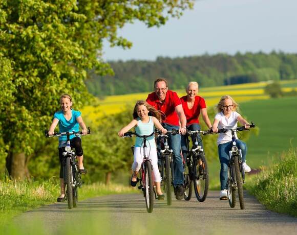 A family cycling on a country road, a sunny ride between green fields