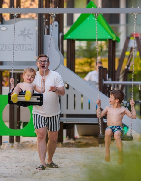Kinder spielen mit Vater auf Spielplatz