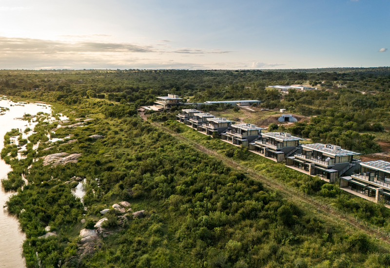Riverfront safari suites in a row, modern private decks overlooking a winding river and lush bushland at sunset