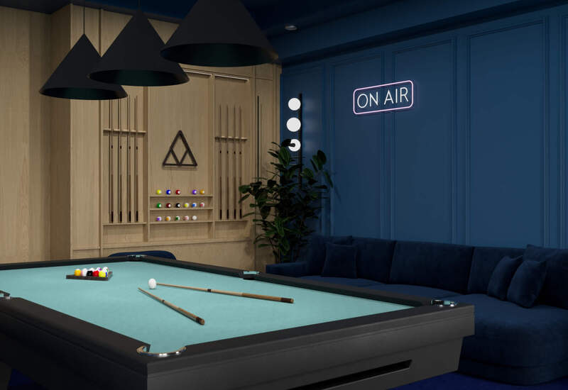 Elegancka sala gier hotelowa z bilardowym stołem w turkusowym suknie, stojakiem na kije, głęboką granatową sofą, wiszącymi lampami i neonem ON AIR