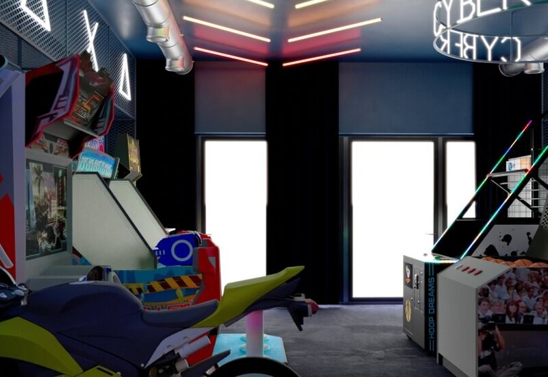 Neonowa sala gier w hotelu z symulatorem wyścigów motocyklowych, automatami i koszykarskim stanowiskiem, odsłoniętą wentylacją i kolorowymi LED.