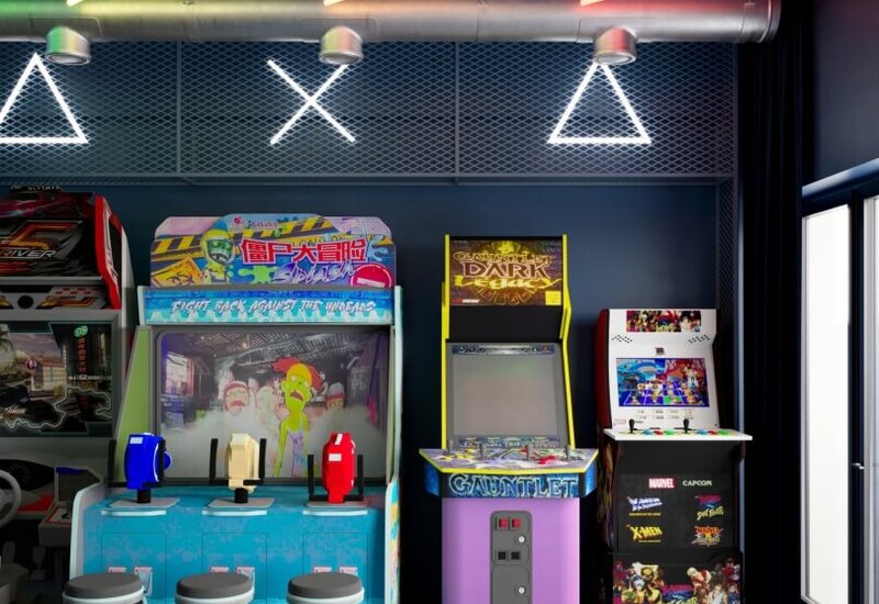 Kolorowa sala gier w hotelu z klasycznymi automatami, trzysiedziskową stacją do gier, neonowym oświetleniem i wykładziną
