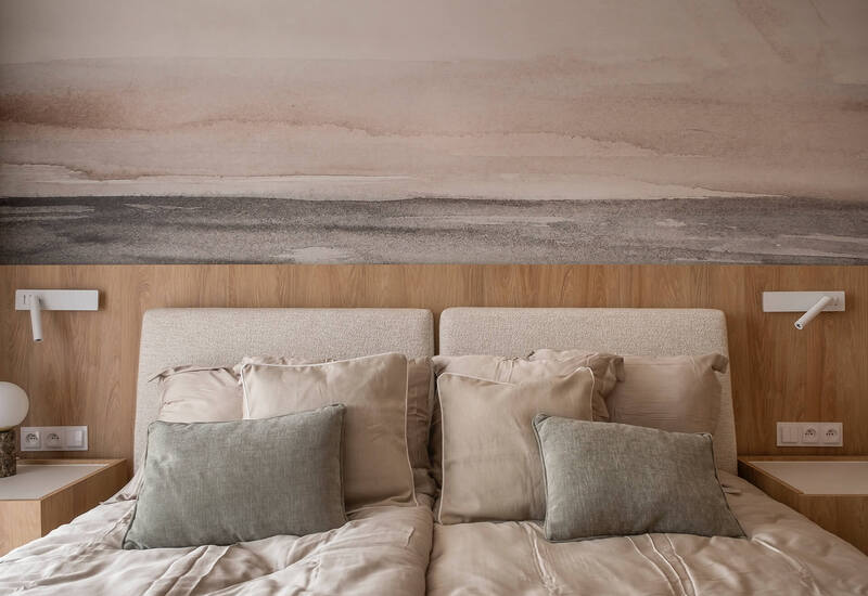 Dwa przylegające łóżka z neutralną pościelą, tapicerowanymi zagłówkami, drewnianymi stolikami nocnymi, lampkami do czytania i obrazem horyzontu.