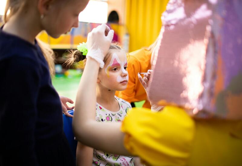 Dziecko podczas malowania twarzy na hotelowej animacji dla dzieci, personel tworzy fantazyjny wzór