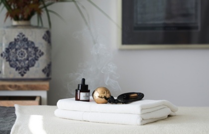 Stół do zabiegów spa z białymi ręcznikami, olejkiem aromaterapeutycznym i unoszącym się dymkiem kadzidła, w spokojnym wnętrzu.