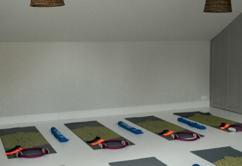 Jasne hotelowe studio pilates z rzędami mat do jogi, obręczami pilates, taśmami oporowymi i wiklinowymi lampami, gotowe na zajęcia grupowe