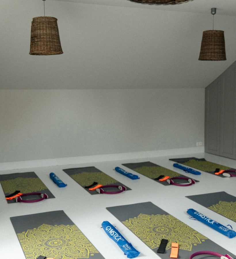 Jasne hotelowe studio pilates z rzędami mat do jogi, obręczami pilates, taśmami oporowymi i wiklinowymi lampami, gotowe na zajęcia grupowe