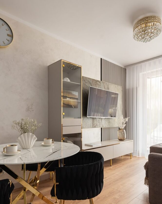 Elegancki salon z marmurowym stołem, czarnymi aksamitnymi krzesłami, złotymi detalami, TV, kanapą i żyrandolem