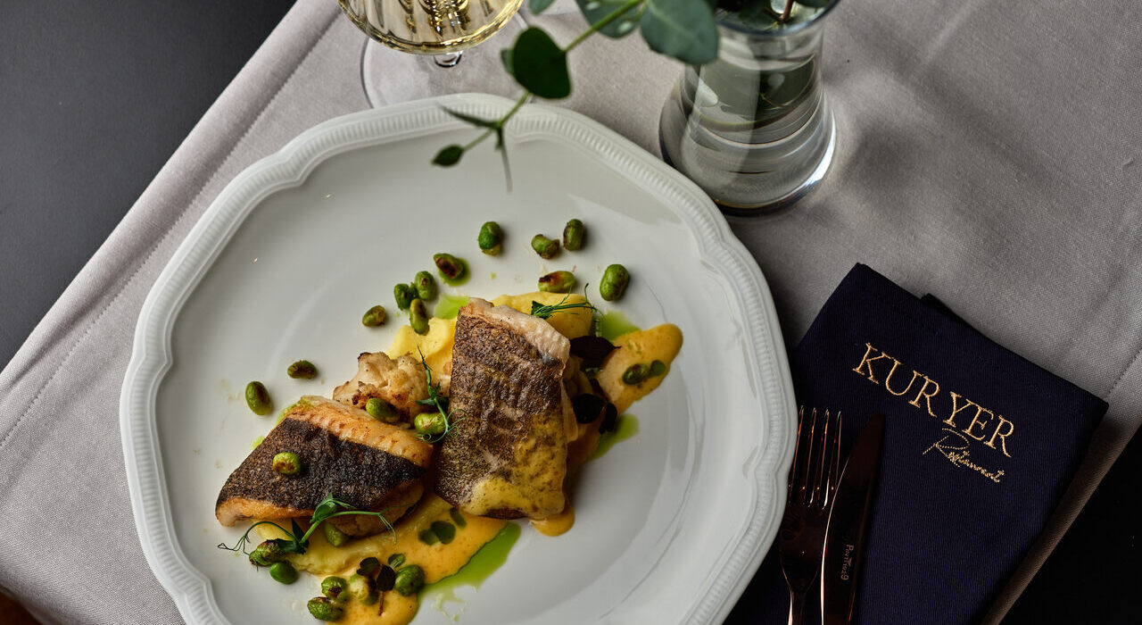 Filet z ryby serwowany z sezonowymi warzywami i ziołami w restauracji Kuryer w Krakowie.