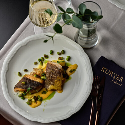 Filet z ryby serwowany z sezonowymi warzywami i ziołami w restauracji Kuryer w Krakowie.