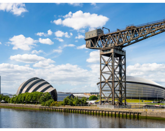 Riverside view of event arenas, iconic crane, riverfront walkway and skyline — waterfront setting for hotel guests