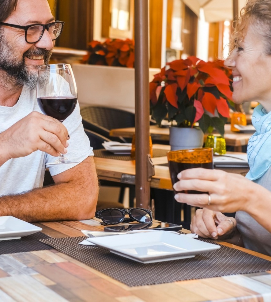 Para ciesząca się winem i napojem w restauracji na zewnątrz z dekoracyjnymi czerwonymi kwiatami i przytulną atmosferą