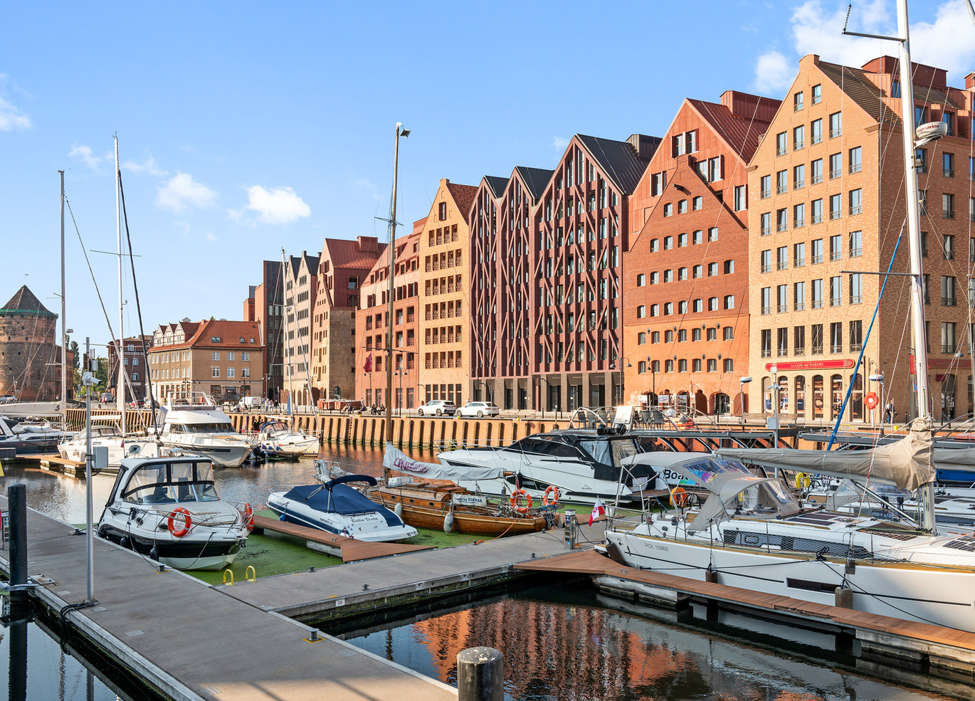 Marina z cumującymi jachtami, nowoczesne czerwone ceglane kamienice ze szczytami i nabrzeżne kawiarnie