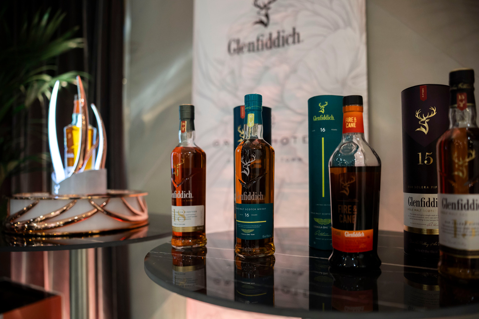 Butelki whisky Glenfiddich na błyszczącym stoliku, firmowe opakowania i ciepłe oświetlenie przy degustacji w hotelu