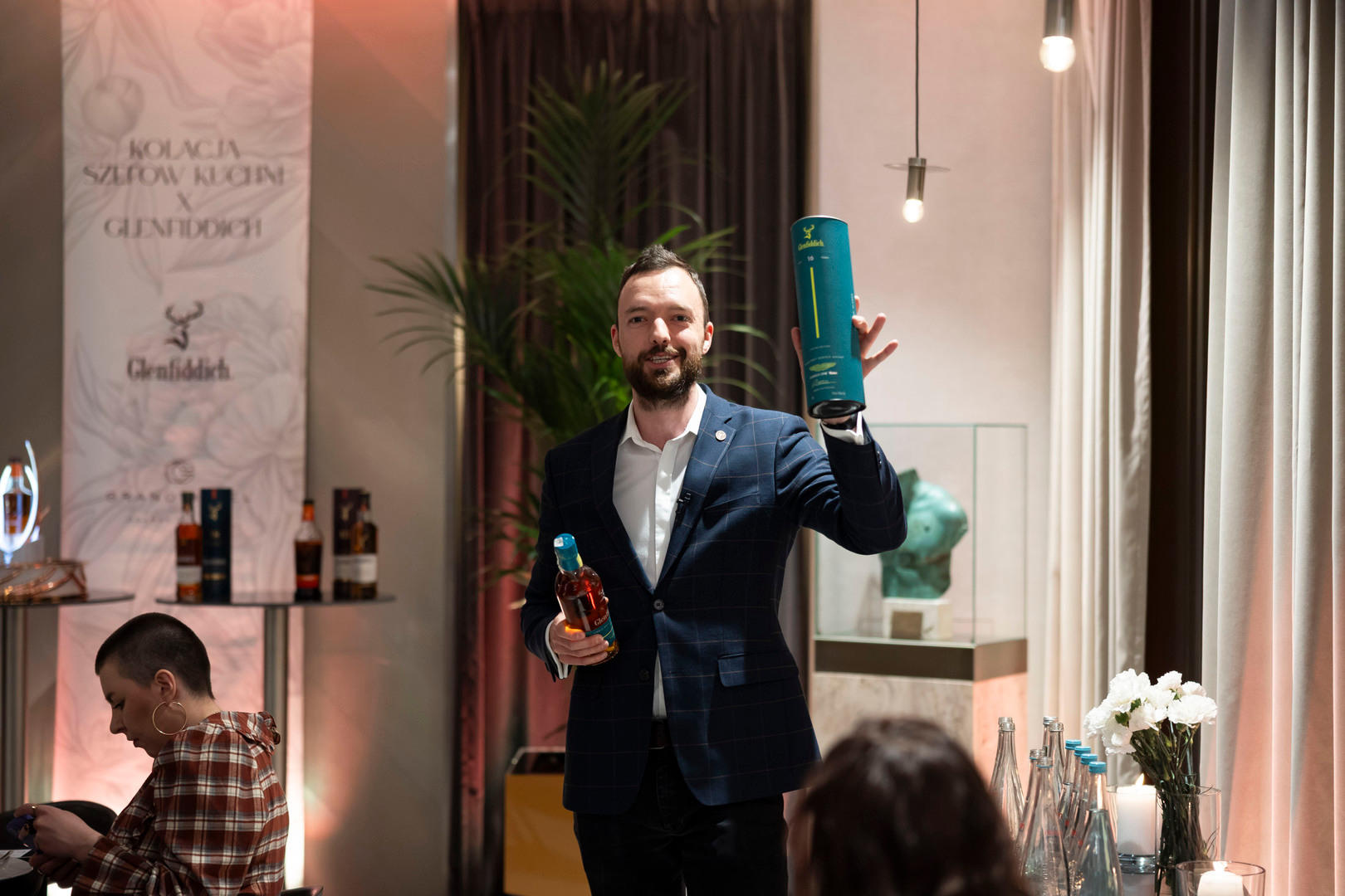 Gospodarz prezentuje whisky Glenfiddich w butelce i tubie podczas kameralnej degustacji w hotelowym lounge