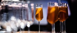 Sparkling amber cocktail in a flute with orange peel on a polished bar, elegant hotel bar setting